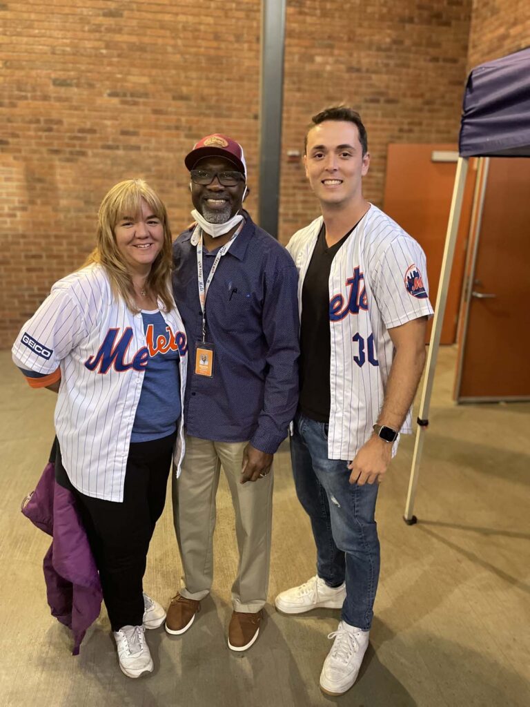 Dr. Heiss at a mets baseball game taking a photo with two other people